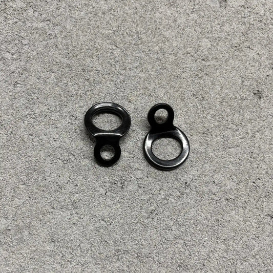 Two black metal eyelets on a gray concrete surface
